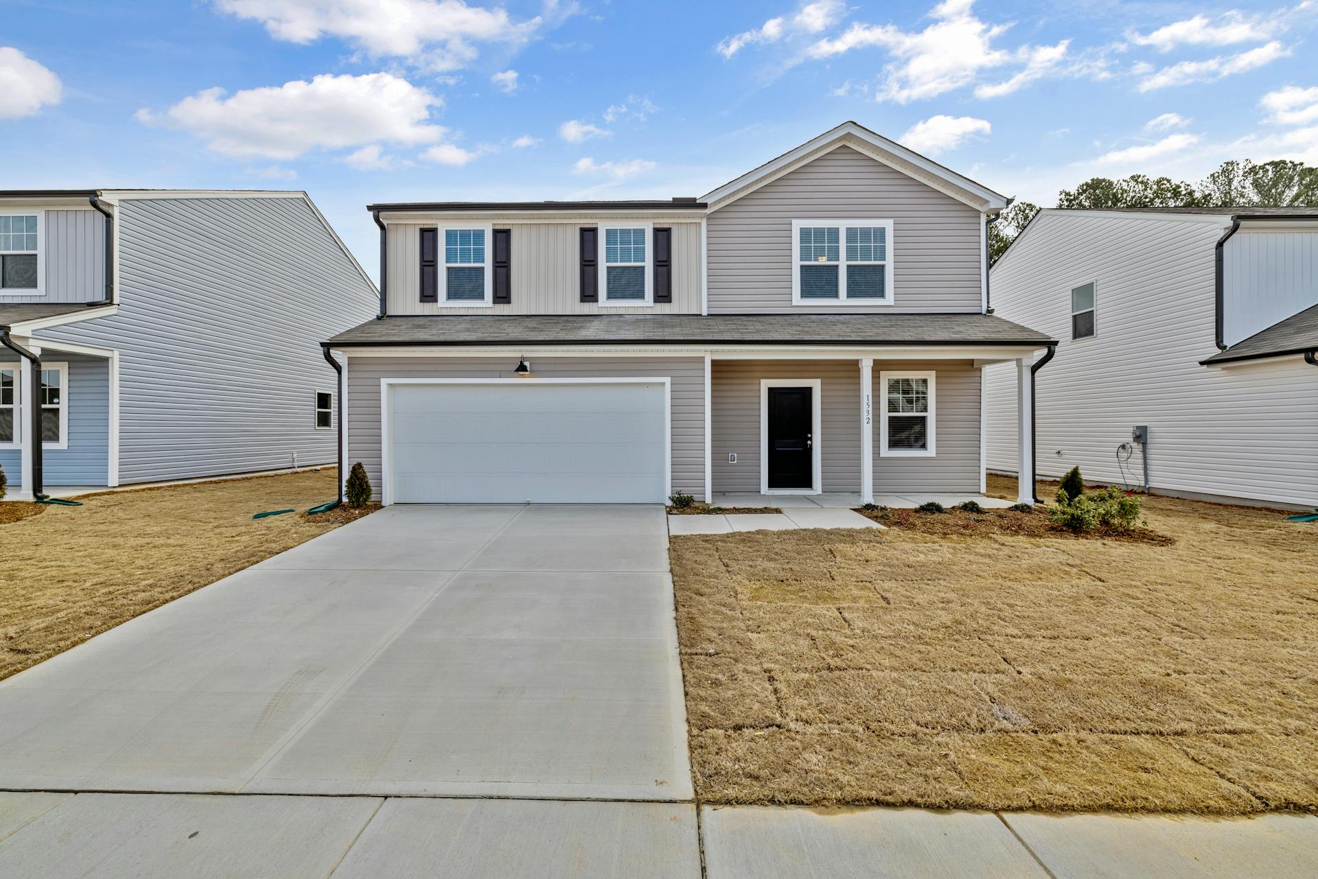 A newly constructed two-story home with light gray vinyl siding and contrasting dark shutters. The house features a large two-car garage, a freshly laid sod lawn, and a welcoming front door, which speaks to the level of professionalism and thoroughness you can expect from a home inspection conducted by Valeri. His services provide homeowners with critical insights and solutions, ensuring their property is primed and polished for potential buyers, as attested by the homeowners' endorsement of his exceptional service and valuable feedback.